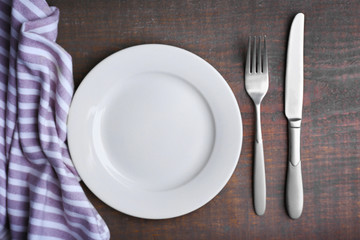 Empty plate with silver cutlery on background