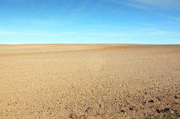 A field of plowed ground on a background of blue sky.