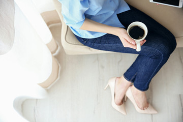 Woman holding a cup of coffee on her lap