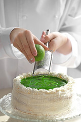Female hands decorating cake  with lime zest