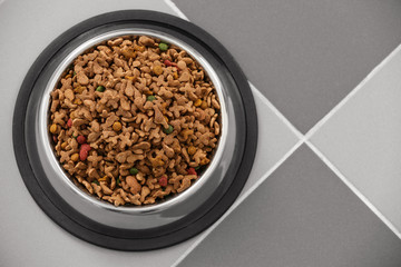 Pet food in a metal bowl on a floor.