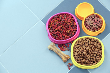 Pet food in  bowls on a floor.
