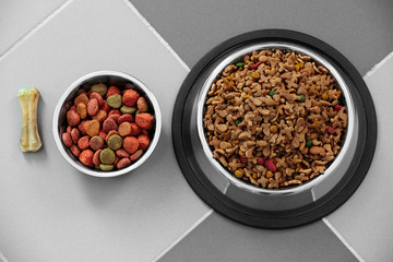 Pet food in  metal bowls on a floor.