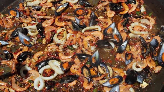 Sofriendo los ingredientes basicos para la preparacion de una paella de marisco al aire libre

