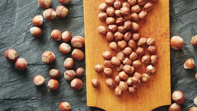 Hazelnuts, filbert on dark wooden background. Dark and moody style. Magic moon and mistic light. Top view with rotation 360