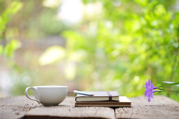 Notebook with pencil and cup on wooden table 