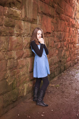 Teenage girl leaning against an old wall with her hands under her chin