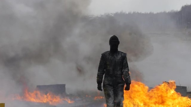 Stunt girl in a fiery explosion. Slow motion. Beautiful girl stunt runs across the field through the explosions and fire.