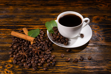 Pile of beans and spices with full cup of coffee