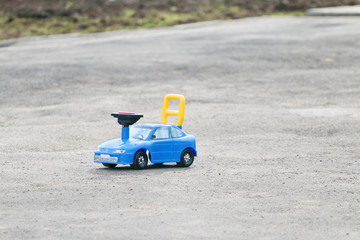 Fototapeta na wymiar Plastic blue toy car is on grey asphalt outdoor at spring day