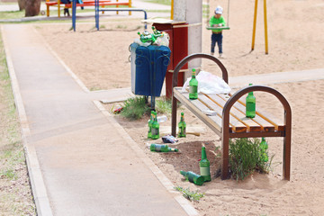 Many beer bottles near bench on children playground at summer 