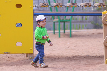 Handsome little boy plays with toy car on children playground