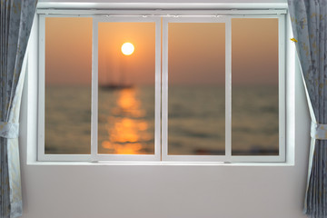 View of sunset on the beach through window - 109447099
