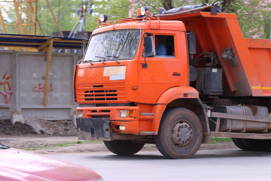 Close up of orange bright truck moving to construction site 