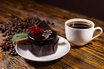 Delicious dark chocolate cupcake by coffee mug