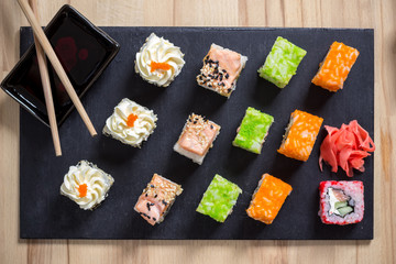 Delicious sushi rolls served on black board with chopsticks