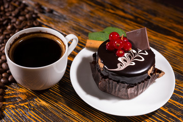 Fresh black coffee in mug by chocolate cupcake