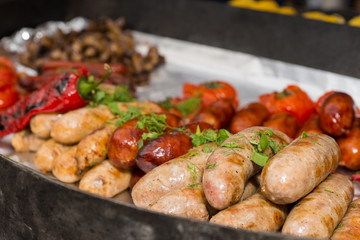 Assorted grilled sausages on a metal tray