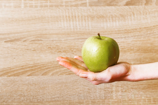 Women's hand keeps green apple.