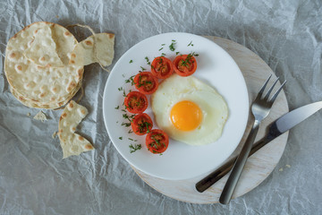 Breakfast made from fried egg, fried cherry tomatoes and bread.