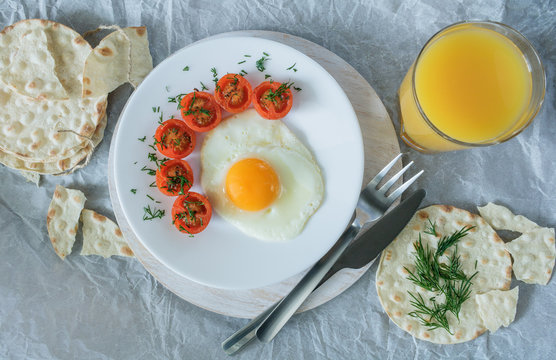Breakfast made from fried egg, fried cherry tomatoes and bread.