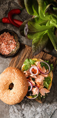 bagel with lettuce and baked salmon on a wooden board,