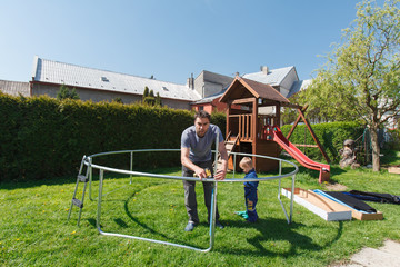 Obraz na płótnie Canvas Father and son when installing large garden trampolines.