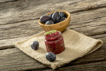 Still life with glass jar of fruit jam, wooden bowl full of ripe