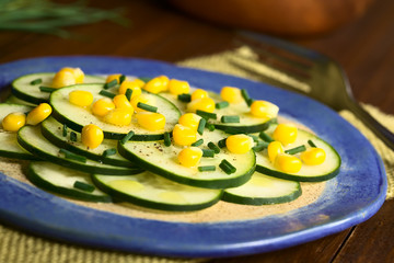 Obraz na płótnie Canvas Fresh cucumber and corn salad with chives served on plate, photographed with natural light (Selective Focus, Focus in the middle of the salad)