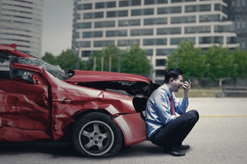 Man with broken car speaks on cellphone