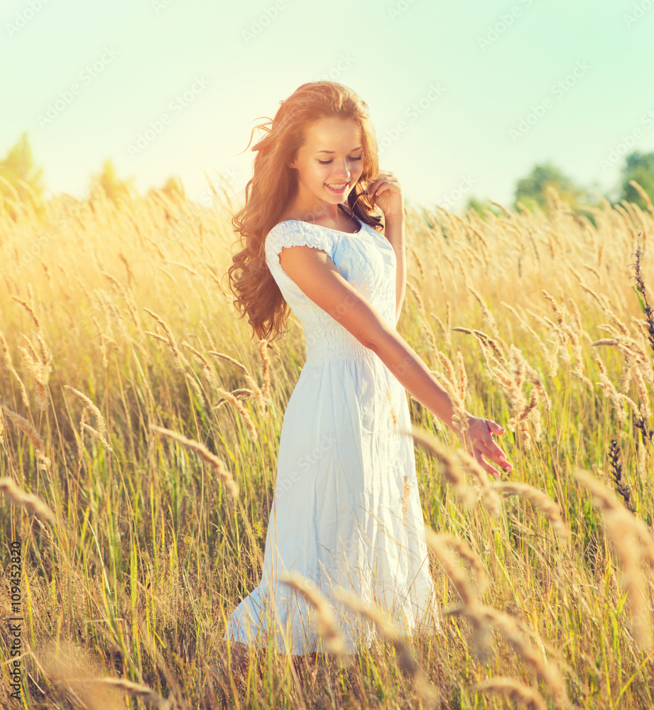 Wall mural Beauty girl outdoors enjoying nature. Beautiful teenage model girl with perfect long curly hair