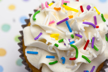 cropped image of a cupcake decorated with sprinkles.