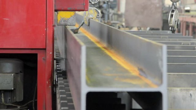 machine drills metal beam in a factory