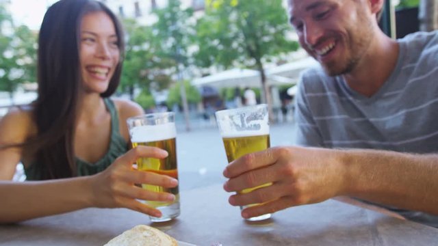 Couple eating tapas drinking beer in Madrid, Spain. Romantic man and woman enjoying local traditional food on square in Madrid. Asian woman and Caucasian man dating. Focus on beer and food.