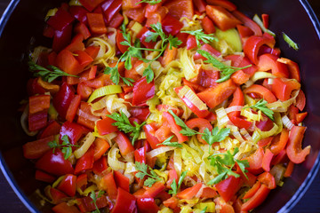 Mixed fresh vegetables (pepper, leek, herbs) in a skillet