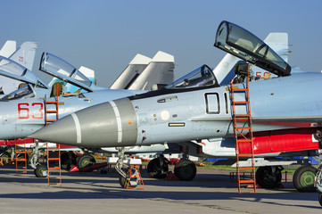 Fighter and bomber jets in row, military multifunction planes with open bulletproof cockpits and ladders for pilots, modern army industry, supersonic air force, blue sky on background
