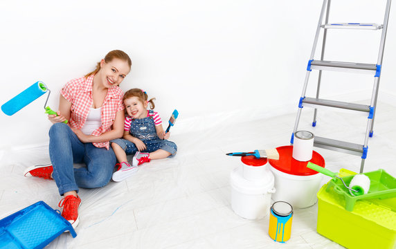 happy family mother and child daughter making repairs, paint wal