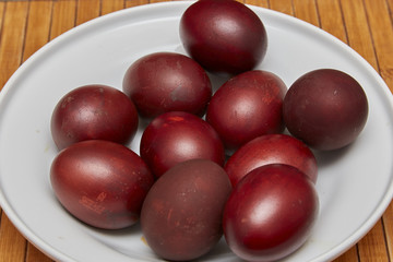 Colorful Easter eggs in a white plate on old wooden table backgr