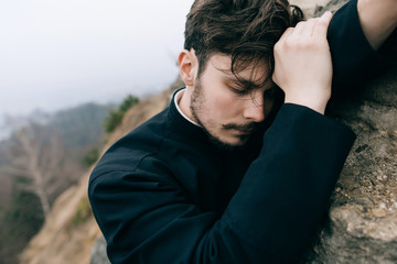 Portrait of handsome catholic bearded man priest or pastor posing outdoors in mountains