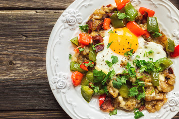 Fried egg with pepper, bacon, potatoes and cilantro