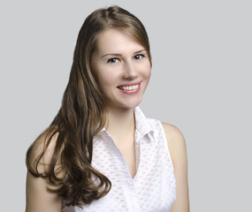 Fototapeta premium Portrait of a beautiful young smiling woman isolated on a gray background
