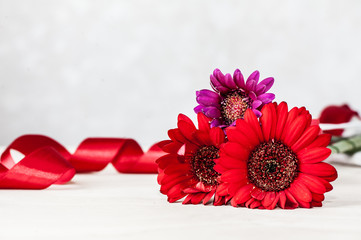 Colorful gerbera flowers with red tape on defocused background
