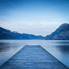 Evening. Background as epic mountain landscape.  Lake at sunset  with wooden pier.