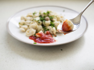 Meat dumpling on a spoon in focus, plate out of focus.
