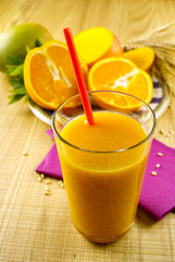 Healthy fresh pressed mango and orange juice with grains and min