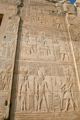 Fototapeta na wymiar stone wall of Egyptian Kom Ombo Temple, with carving figures and hieroglyphs, with ceremony people, priest, pharaoh or king, goddess or queen, in Egypt, Africa