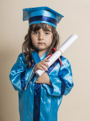Small boy graduation from kindergaten with blue formal dress with rolled paper in his hand