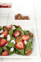 delicious spinach salad with strawberry slices and pecan nuts