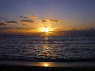 Dramatic Sunset dropping behind the ocean shining over boats