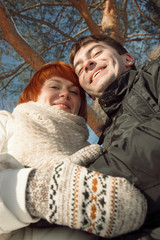 Happy smiling couple in winter park under tree